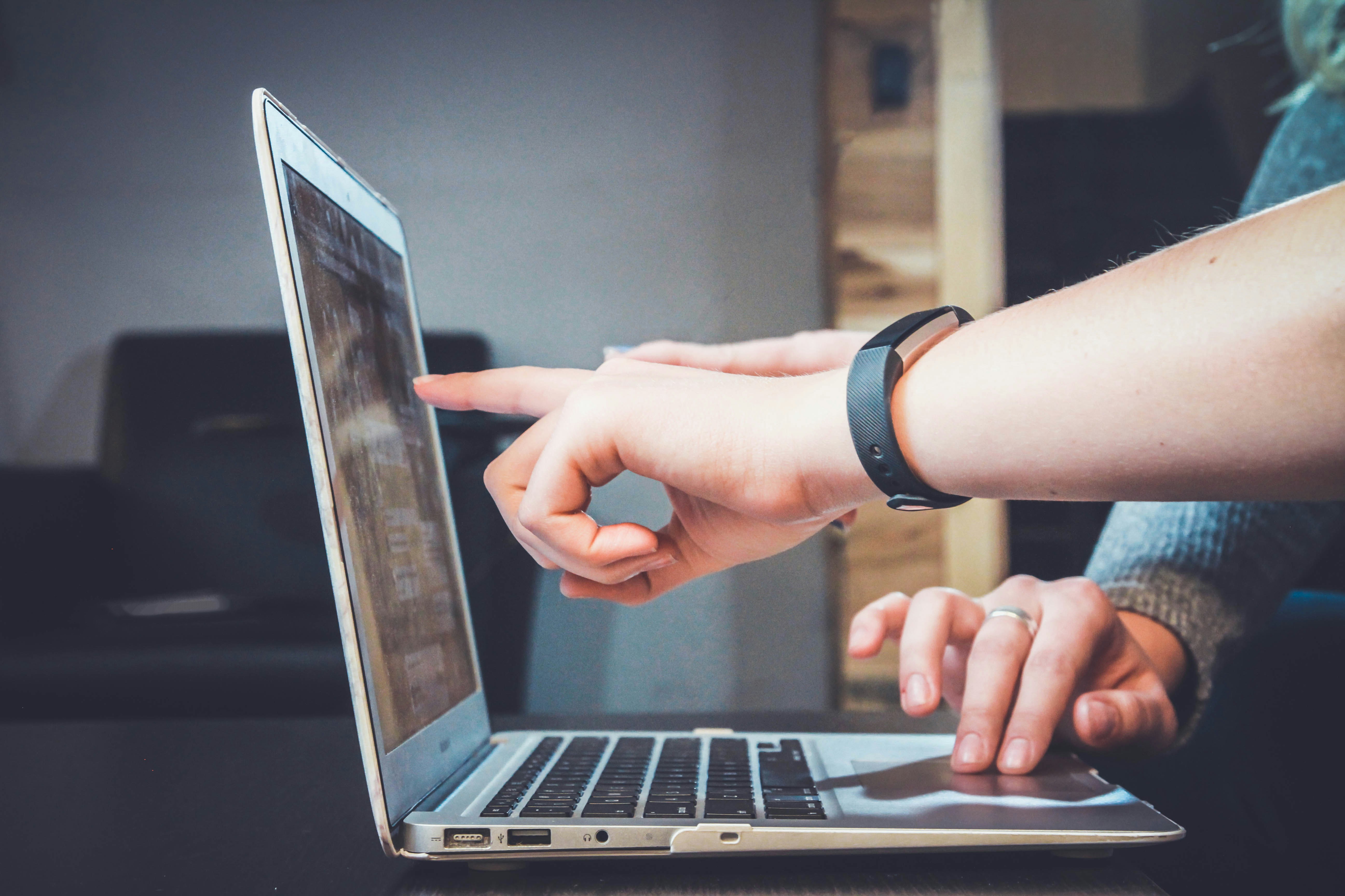 Two people collaborating on a laptop, illustrating the importance of reviewing commits before pushing to public repository to ensure code quality and security.